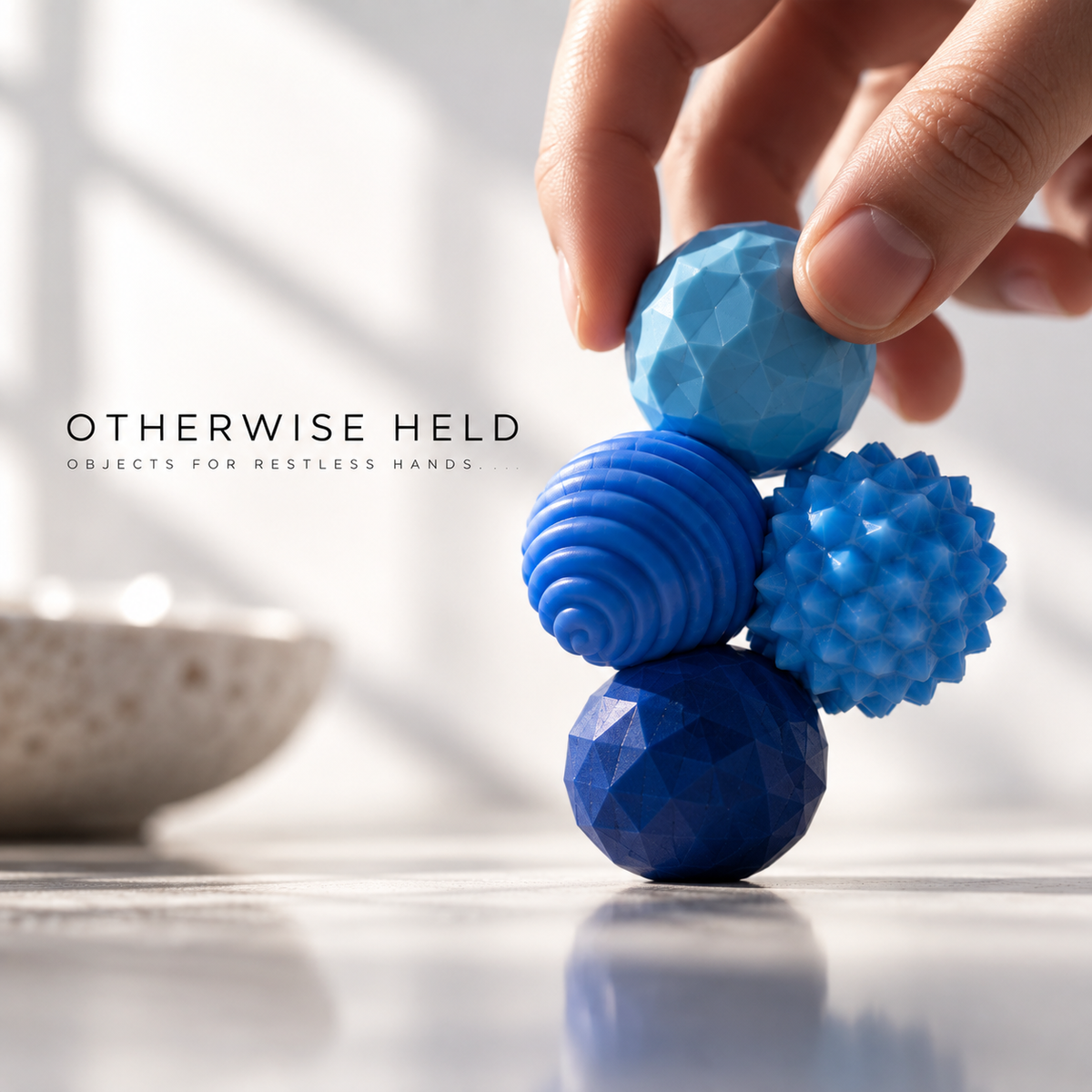 OH 01 Magnetic, four textured blue magnetic spheres stacked in a hand