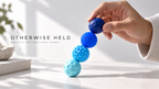 Hand pulling apart a chain of blue OH 01 Magnetic spheres