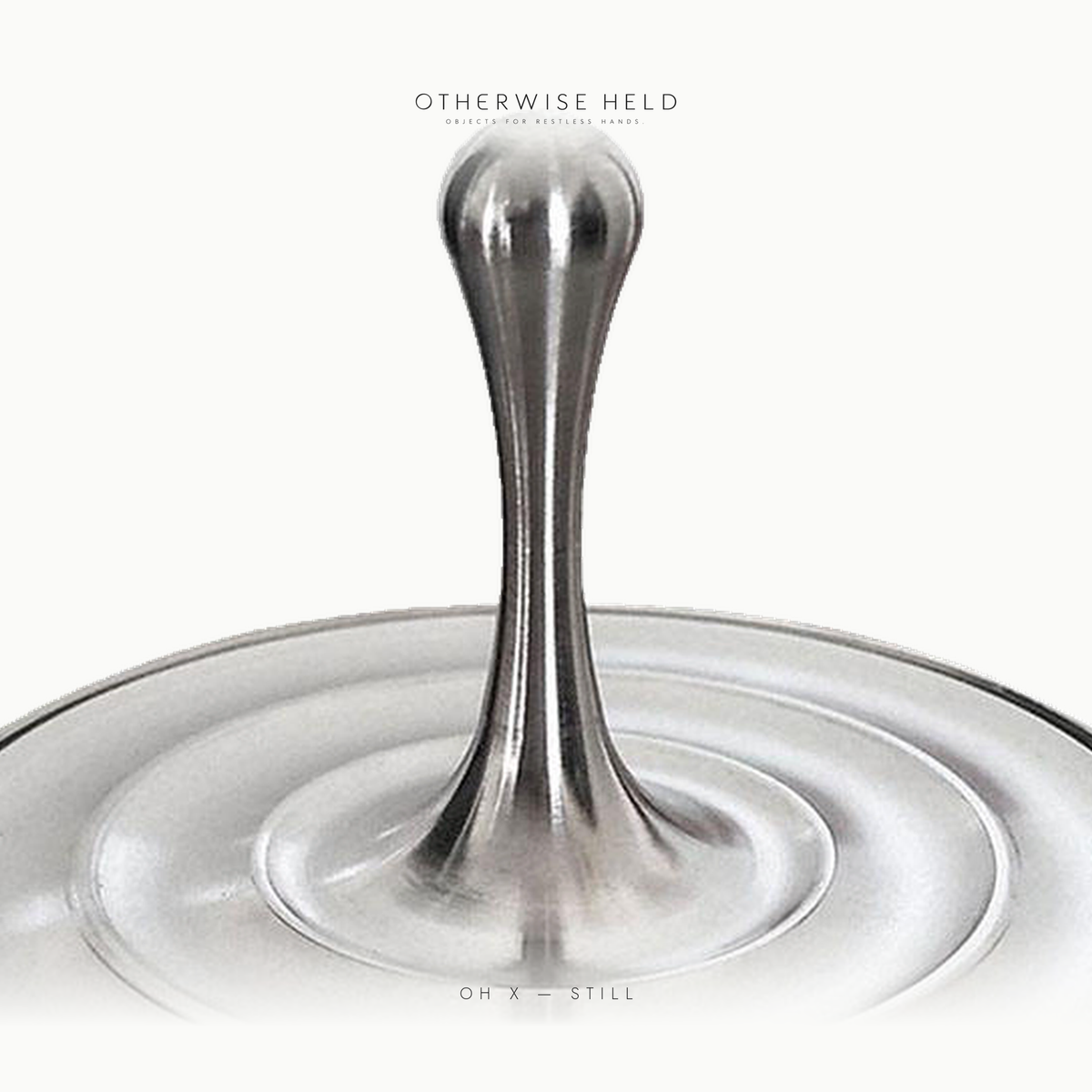 Close-up of OH X Still spinning top stem and rippled steel base, premium executive desk toy