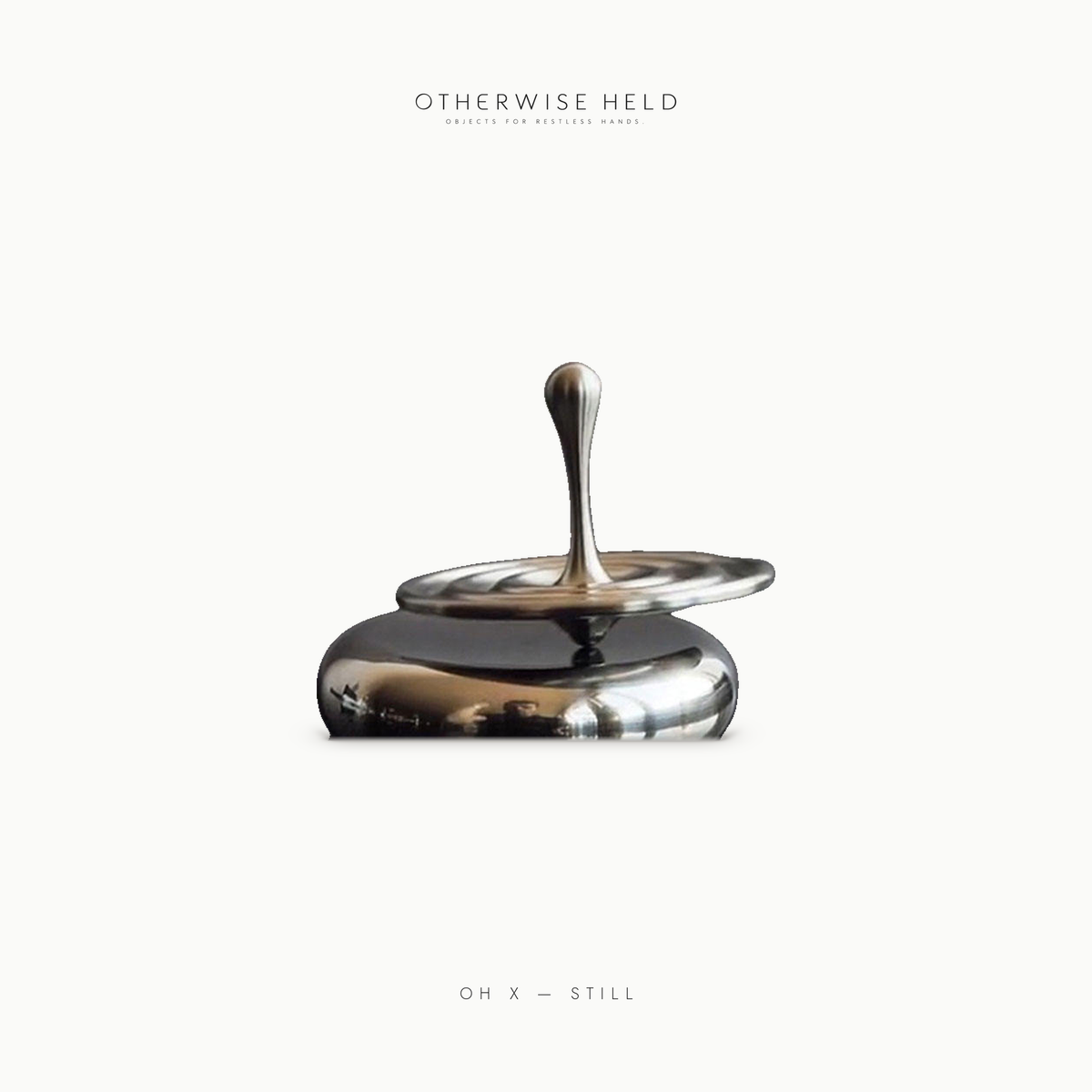 OH X Still stainless steel spinning top, side view spinning on mirror-polished base