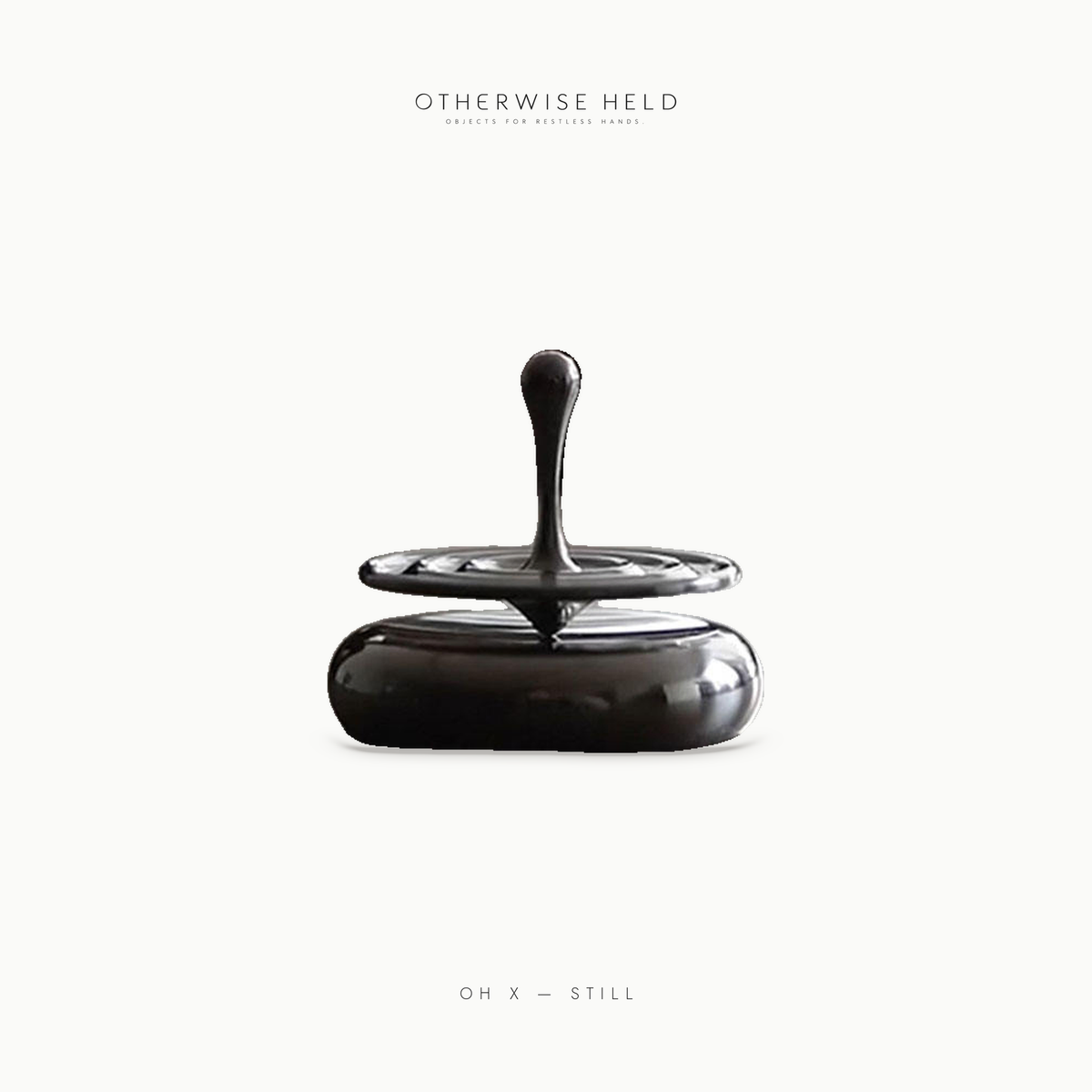 OH X Still metal desk spinning top in motion above its polished steel base